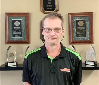 A SERVPRO employee taking a picture in front of awards to update the employee photos