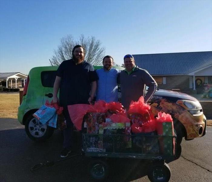 SERVPRO employee standing with 2 guys behind christmas presents